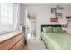 Bright bedroom with a green bed frame, and a door opening to a balcony with an outdoor chair set at 4451 S Ammons St # 5-307, Littleton, CO 80123