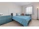 Bright bedroom featuring a bed with blue patterned cover, matching dresser, and natural light from the window at 4451 S Ammons St # 5-307, Littleton, CO 80123