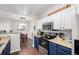 Modern kitchen with white upper cabinets, blue lower cabinets, stainless appliances, and hardwood floors. Dining area nearby at 4451 S Ammons St # 5-307, Littleton, CO 80123