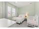 Bright bedroom featuring a white bed and crib, complemented by mint green walls and natural light from large windows at 9080 W 100Th Way, Broomfield, CO 80021