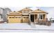 Charming brown two-story home featuring a two-car garage and inviting front porch, surrounded by a snowy landscape at 19473 W 58Th Pl, Golden, CO 80403