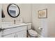 Cozy powder room with modern fixtures, decorative art, and a round framed mirror at 12450 Watkins Rd, Hudson, CO 80642