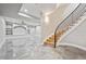 Spacious living room features a curved staircase, built-in shelving, and modern tile flooring at 12450 Watkins Rd, Hudson, CO 80642