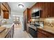 Functional kitchen with wooden cabinets, tiled floors, stainless steel appliances, and view to the dining area at 1390 S Glencoe St, Denver, CO 80222