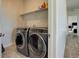 This laundry room features gray front-load washer and dryer with white shelving perfect for storing laundry supplies at 14290 Hop Clover St, Parker, CO 80134