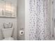 Well-lit bathroom with a toilet, basket storage, decorative shower curtain, and neutral tones at 606 Beth Ave, Fort Lupton, CO 80621