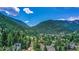 An aerial view showcases a charming town nestled amongst lush green trees and mountains under a bright sky at 1890 Argentine St # C301, Georgetown, CO 80444