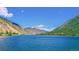 A tranquil lake is surrounded by mountains under a clear sky, reflecting the natural beauty of the landscape at 1890 Argentine St # C301, Georgetown, CO 80444