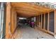 Enclosed carport or storage area with wooden beams, gravel floor, and ample storage space at 6066 S Monaco Way, Centennial, CO 80111