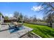 A cozy patio set on a concrete slab offers an outdoor living space with a blue rug and a view of the grassy backyard at 6074 S Dudley Way, Littleton, CO 80123