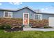 Charming front entrance with a red door, stone exterior accents, manicured landscaping, and vibrant flower pots at 6074 S Dudley Way, Littleton, CO 80123