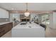 Stylish kitchen island with seating, pendant lighting, and an open view into the living room area with a fireplace at 5951 S Akron Way, Greenwood Village, CO 80111