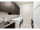 Functional laundry room featuring modern washer and dryer, ample cabinet storage, and a sink at 32 Jackson St, Denver, CO 80206
