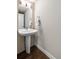 Modern powder room with a pedestal sink, wood-look tile accent wall, and hardwood floors at 32 Jackson St, Denver, CO 80206