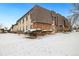 Exterior view showcasing a two-story building with stone and siding details, plus snowy landscaped grounds at 9650 Huron St # 22, Thornton, CO 80260