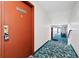 Hallway featuring patterned carpeting and a bright orange apartment door with a key lockbox at 9650 Huron St # 22, Thornton, CO 80260