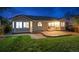 A home's back exterior shows a lawn, patio, bay windows, and neutral siding at dusk at 10060 Oak Leaf Way, Highlands Ranch, CO 80129
