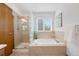 The bathroom features a glass-enclosed shower next to a soaking tub and a large sunny window at 10894 Depew Pl, Westminster, CO 80020
