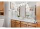 Bathroom with white countertop, wood cabinets, framed mirror, and decorative lighting at 10894 Depew Pl, Westminster, CO 80020