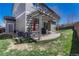 Covered back patio area with a grill, umbrella, and well-manicured lawn at 2976 Open Sky Way, Castle Rock, CO 80109