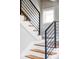 Modern staircase with wood treads, white risers, and sleek black metal railings, enhanced by natural light from a nearby window at 2931 W 20Th Ave, Denver, CO 80211