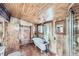 A quaint bathroom featuring wood paneled walls, and a classic clawfoot tub with a vintage shower fixture at 5502 Santa Clara Rd, Indian Hills, CO 80454