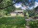 Exterior view of a green home with a brick pathway, surrounded by lush greenery, providing a serene ambiance at 5502 Santa Clara Rd, Indian Hills, CO 80454