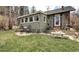 Cozy home exterior with a sunroom, stone patio, and well-maintained lawn at 5502 Santa Clara Rd, Indian Hills, CO 80454
