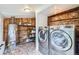 Functional laundry room featuring wood paneled walls, modern washer and dryer, and plenty of room for storage at 5502 Santa Clara Rd, Indian Hills, CO 80454
