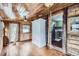 Cozy living room with wood paneled walls and hardwood flooring plus view into a kitchen at 5502 Santa Clara Rd, Indian Hills, CO 80454