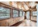 Sun room with wood paneled walls, hardwood floors, and multiple windows offering natural light at 5502 Santa Clara Rd, Indian Hills, CO 80454
