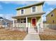 Two-story house with a green exterior, front porch, and red door at 9437 E 108Th Dr, Commerce City, CO 80640