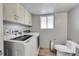 Functional laundry room features front-loading washer/dryer, storage cabinets, and adjacent toilet at 2518 S Ouray Way, Aurora, CO 80013