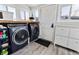 Bright laundry room with front loading washer and dryer, storage and white door at 1308 S Sherman St, Denver, CO 80210
