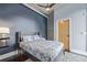 Bedroom with a ceiling fan, blue accent wall, and a wooden door at 3100 Huron St # 2D, Denver, CO 80202