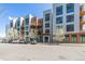 Apartment building with brick and white siding with parking, green grass, and trees at 3100 Huron St # 2D, Denver, CO 80202