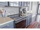 A kitchen with stainless steel appliances, butcher block countertops, gray backsplash, and blue cabinets at 3100 Huron St # 2D, Denver, CO 80202