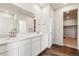 Bright bathroom featuring double vanity with white cabinets and a view to the walk-in closet at 14390 Heritage Dr, Mead, CO 80504