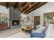 Open-concept living room featuring a stone fireplace, wood beams, and seamless transition to dining area at 1290 S Lininger Dr, Golden, CO 80401
