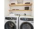 Modern laundry room with front load washer and dryer, and floating shelves at 5128 W 26Th Ave # 207, Denver, CO 80212