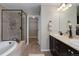 Elegant bathroom featuring dual sinks, a soaking tub, glass enclosed shower and a view into the large walk-in closet at 9592 Firenze Way, Highlands Ranch, CO 80126