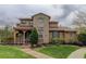 Charming stone home with a well-manicured lawn and inviting front porch with a wood-supported roof at 9592 Firenze Way, Highlands Ranch, CO 80126