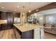Modern kitchen with island seating, stainless steel appliances, and an open layout, flowing into the living room at 9592 Firenze Way, Highlands Ranch, CO 80126