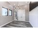 Bright entry room with sleek gray floors, modern light fixture, and doorway to bathroom at 56520 E 74Th Ave, Strasburg, CO 80136