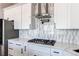Gourmet kitchen features white cabinets, gas range, pot filler, and tile backsplash at 56520 E 74Th Ave, Strasburg, CO 80136