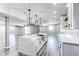 Open-concept kitchen with a large quartz island, modern lighting, and gray wood flooring at 56520 E 74Th Ave, Strasburg, CO 80136