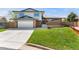 Charming home with a brick and siding exterior, green lawn, and an attached garage with concrete driveway at 13390 W Warren Ave, Lakewood, CO 80228