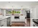 Bright open kitchen offers stainless appliances, island, and expansive view of lush trees from the windows at 13390 W Warren Ave, Lakewood, CO 80228