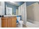 Bright bathroom with white tiled shower, wood vanity and blue colored walls at 6273 Torrey Ln, Arvada, CO 80403