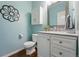 Charming powder room with light blue walls, white vanity, and decorative mirror at 6273 Torrey Ln, Arvada, CO 80403